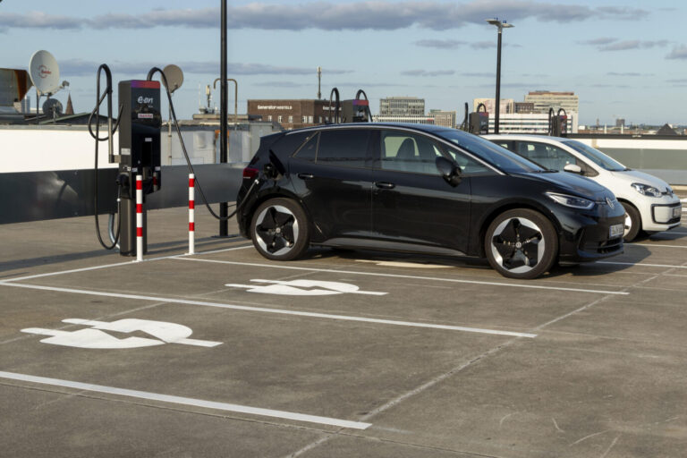 Ein schwarzes E-Auto von Volkswagen lädt an einer Elektrolade-Station. Im Vordergrund ist ein Parkplatz zu sehen