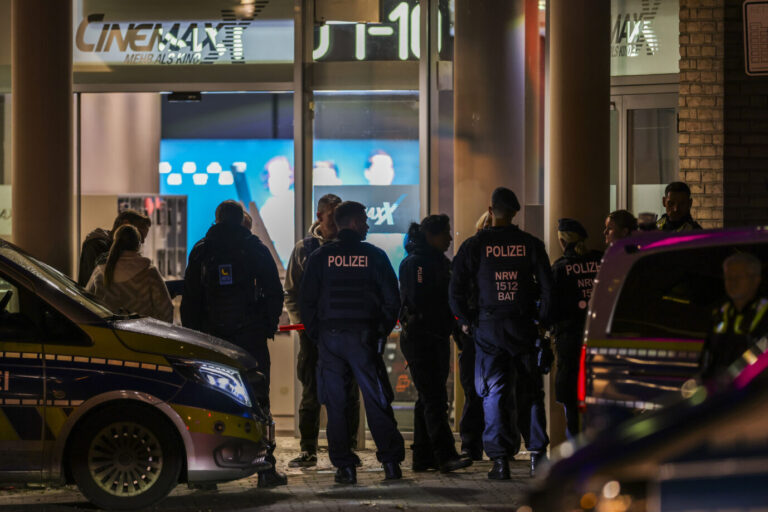 Polizeibeamte und Rettungsdienst stehen vor dem Cinemaxx-Kino in der Krefelder Innenstadt. Im Foyer eines großen Kinos am Hauptbahnhof in Krefeld hat die Polizei einen Verdächtigen niedergeschossen. An drei Stellen in der Stadt habe es Brände gegeben, die mutmaßlich der Verdächtige verursacht habe.