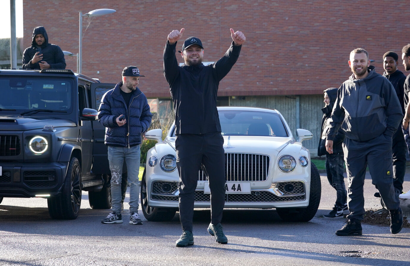 Der verurteilte Entführer und Gewalttäter Daniel Dowling-Brooks steht vor einem weißen Auto und hebt triumphierend seine Arme. Daneben stehen seine Kumpels. Dowling-Brooks wurde vorzeitig aus dem Knast entlassen