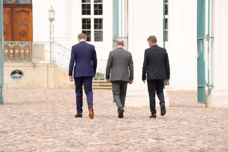 Auf einem Schloßgelände in Brandenburg gehen Finanzminister Christian Lindner (FDP), Bundeskanzler Olaf Scholz (SPD) und Wirtschaftsminister Robert Habeck (Grüne), mit dem Rücken zum Betrachter, auf das Schloß zu. Symbolbild für verkommende deutsche Politiker