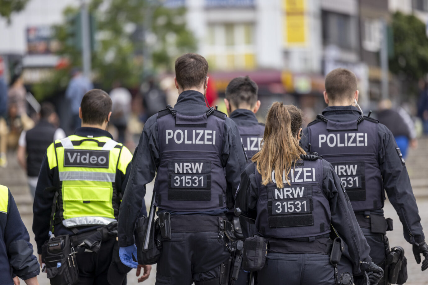 Vier Männer und eine Frau, alle in Uniformen der Kölner Polizei, laufen durch die Innenstadt. Möglicherweise sind sie auf dem Weg zu einem Tatort der Mocro-Mafia