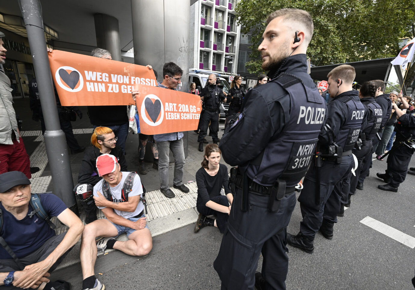 Polizisten bewachen Klimaaktivisten «der letzten Generation» in der Innenstadt, nachdem diese versucht hatten eine Strasse zu blockieren, um auf ihre Angelegenheit aufmerksam zu machen.