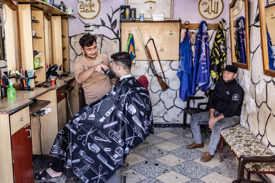 Ungewöhnlicher Friseurbesuch – mit der Waffe an der Wand im syrischen Aleppo. Foto: picture alliance/dpa | Anas Alkharboutli