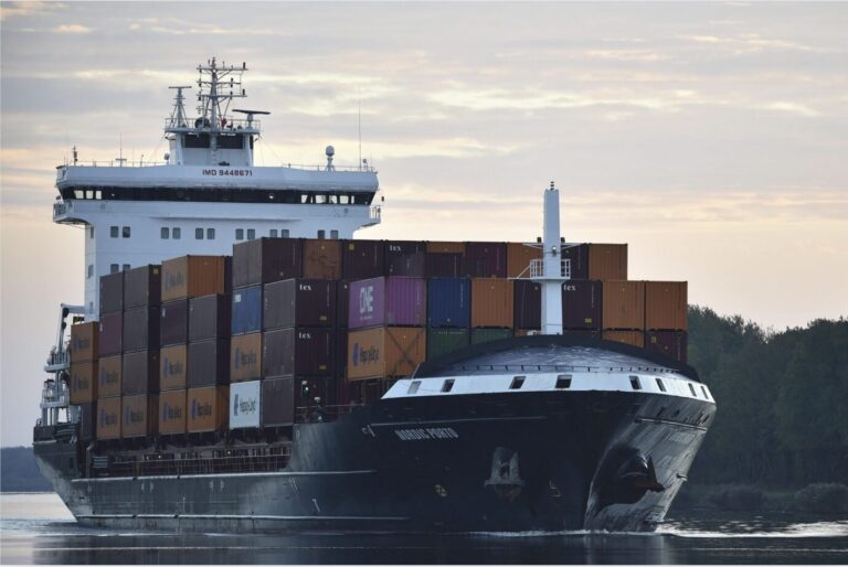 Ein riesiges, mit Containern beladenes Schiff fährt den Kielkanal in Schleswig-Holstein entlang – Symbolbild um Lieferkettengesetz