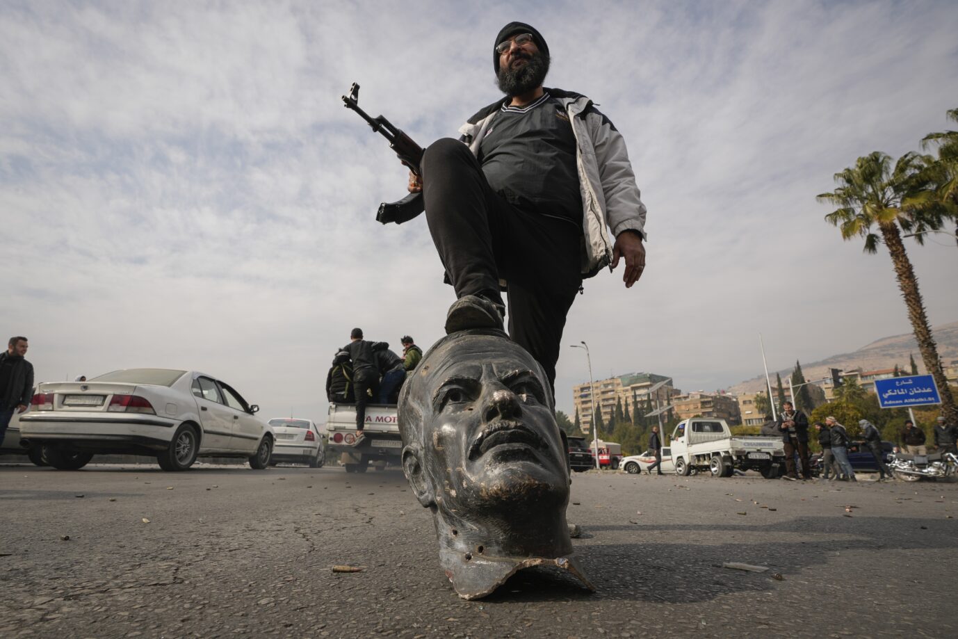 An opposition fighter steps on a broken bust of the late Syrian President Hafez Assad in Damascus, Syria, Sunday Dec. 8, 2024. (AP Photo/Hussein Malla) Syrien am Ende?