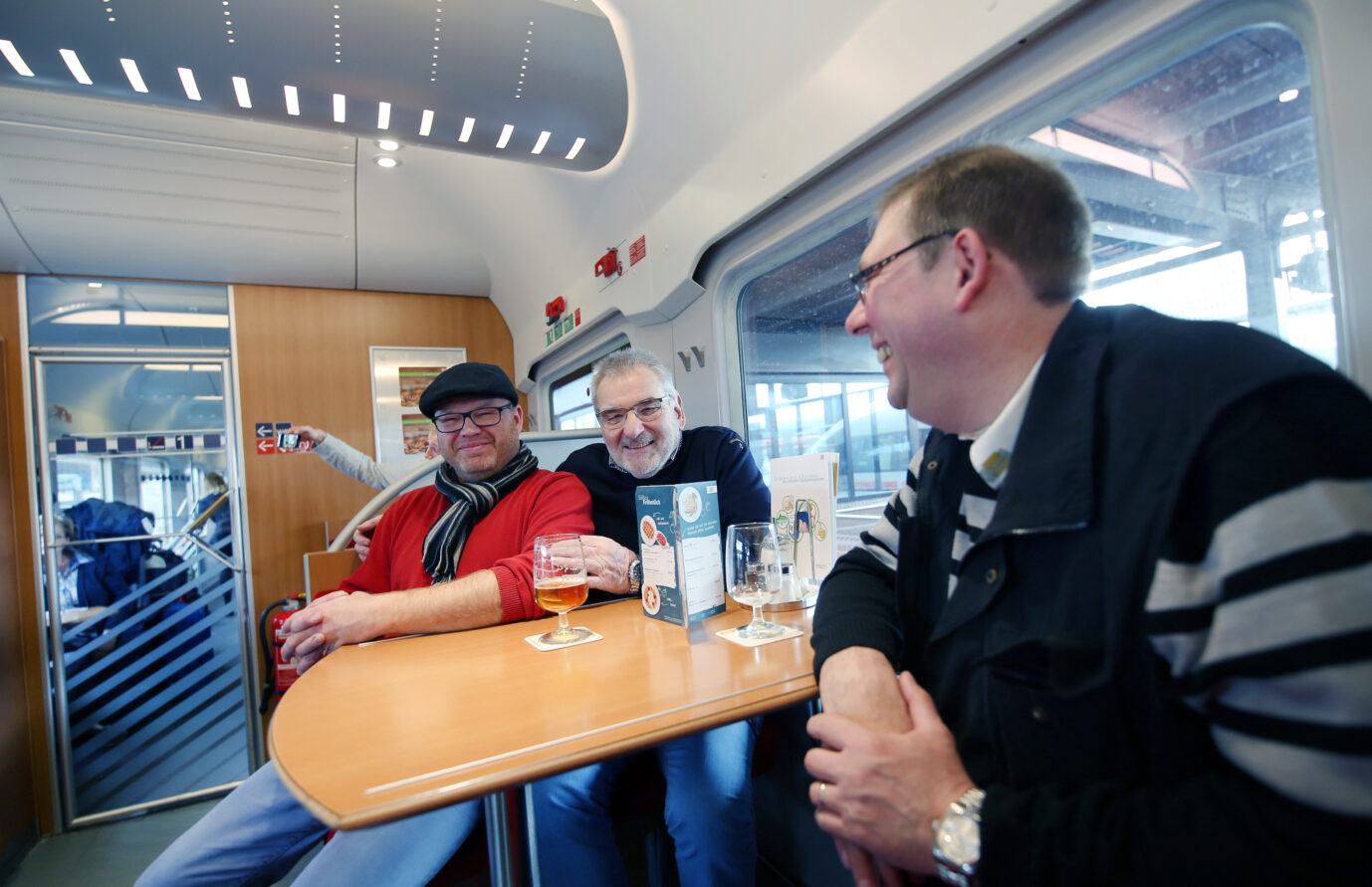 Die Fahrgäste Daniel Kontermann (l), Wolfgang Regert und Jörg Meitz (r) sitzen am 29.10.2017 am Bahnhof von Dortmund (Nordrhein-Westfalen) im Bordbistro des Hotelzuges und warten auf die Weiterfahrt nach Hamburg. Der Zugverkehr in Richtung Norden wurde wegen des Herbststurms Herwart eingestellt. Fahrgäste genießen ein gezapftes Bier im Bordbistro: Die Deutsche Bahn stellt komplett auf Flaschenbier um. Foto: picture alliance / Ina Fassbender/dpa | Ina Fassbender