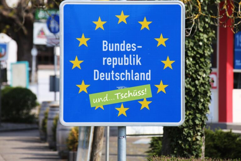 Symbolbild Auswandern Grenzschild der Bundesrepublik Deutschland mit Aufkleber und tschüss