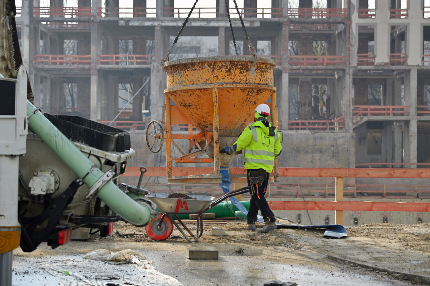 Ein Bauarbeiter in einer gelben Jacke arbeitet auf einer Baustelle – hier entsteht ein neues Haus und das sieht man dank der sinkenden Genehmigungen für Wohnungsbauten in Deutschland immer seltener