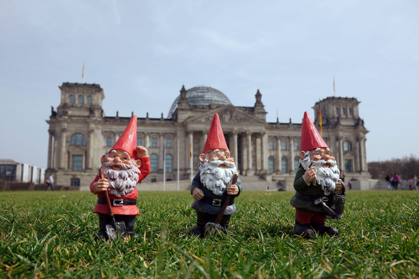 Drei Gartenzwerge stehen vor dem Reichstagsgebäude am Platz der Republik in Berlin-Tiergarten. Sie müssen draußenbleiben: Zahlreiche Kleinparteien verlieren wertvolle Stimmanteile. Foto: picture alliance / ZB | Sascha Steinach