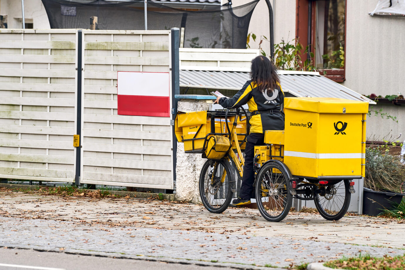 Eine Postbotin der Deutschen Post bei der Zustellung von Briefen mit dem Fahrrad. Symbolbild: picture alliance / CHROMORANGE | Michael Bihlmayer