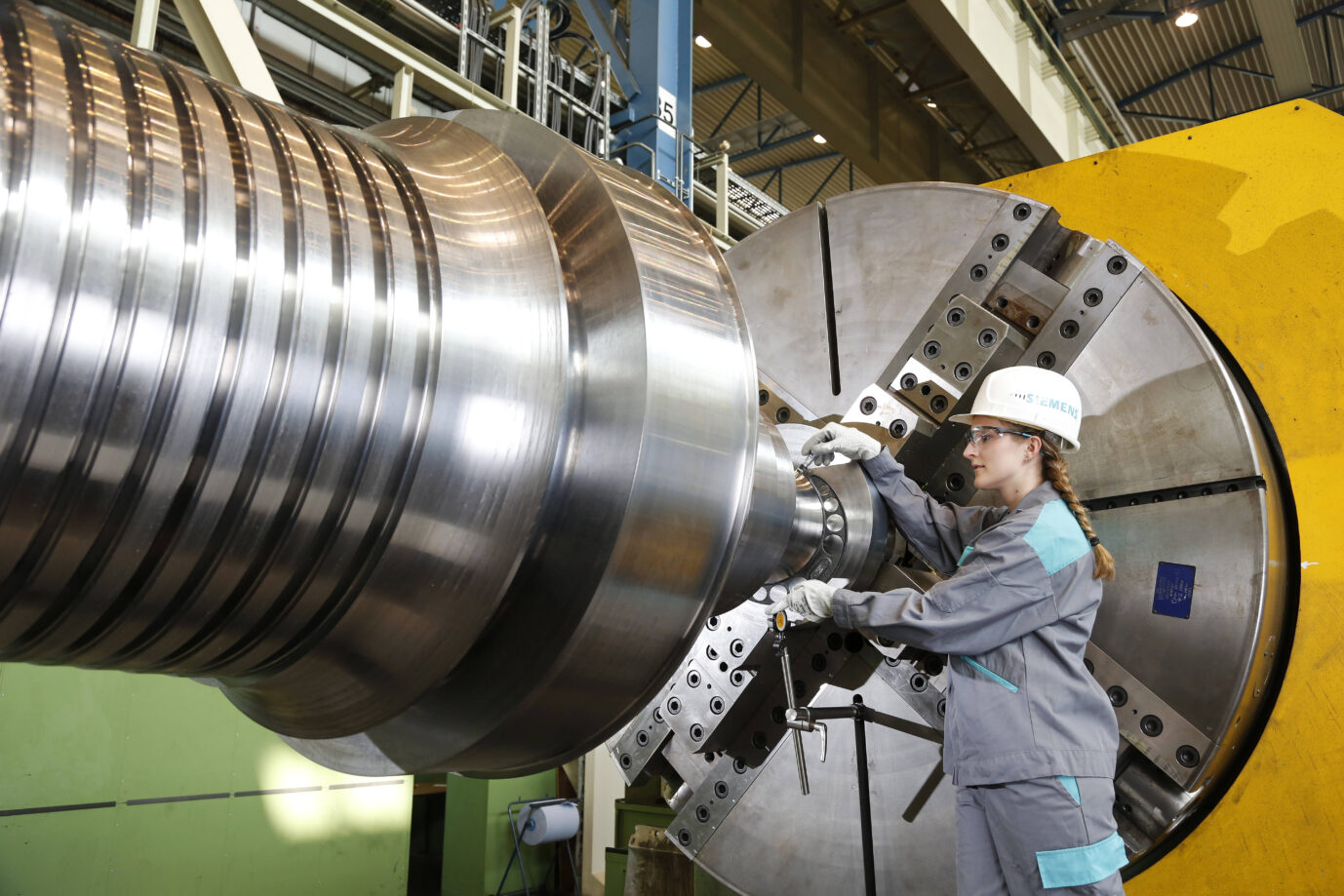 Eine Frau, Ingenieurin, mit Siemens-Helm arbeitet in einer Fabrik von Siemens … nach dem kommenden Stellenabbau tut sie das vielleicht aber bald nicht mehr