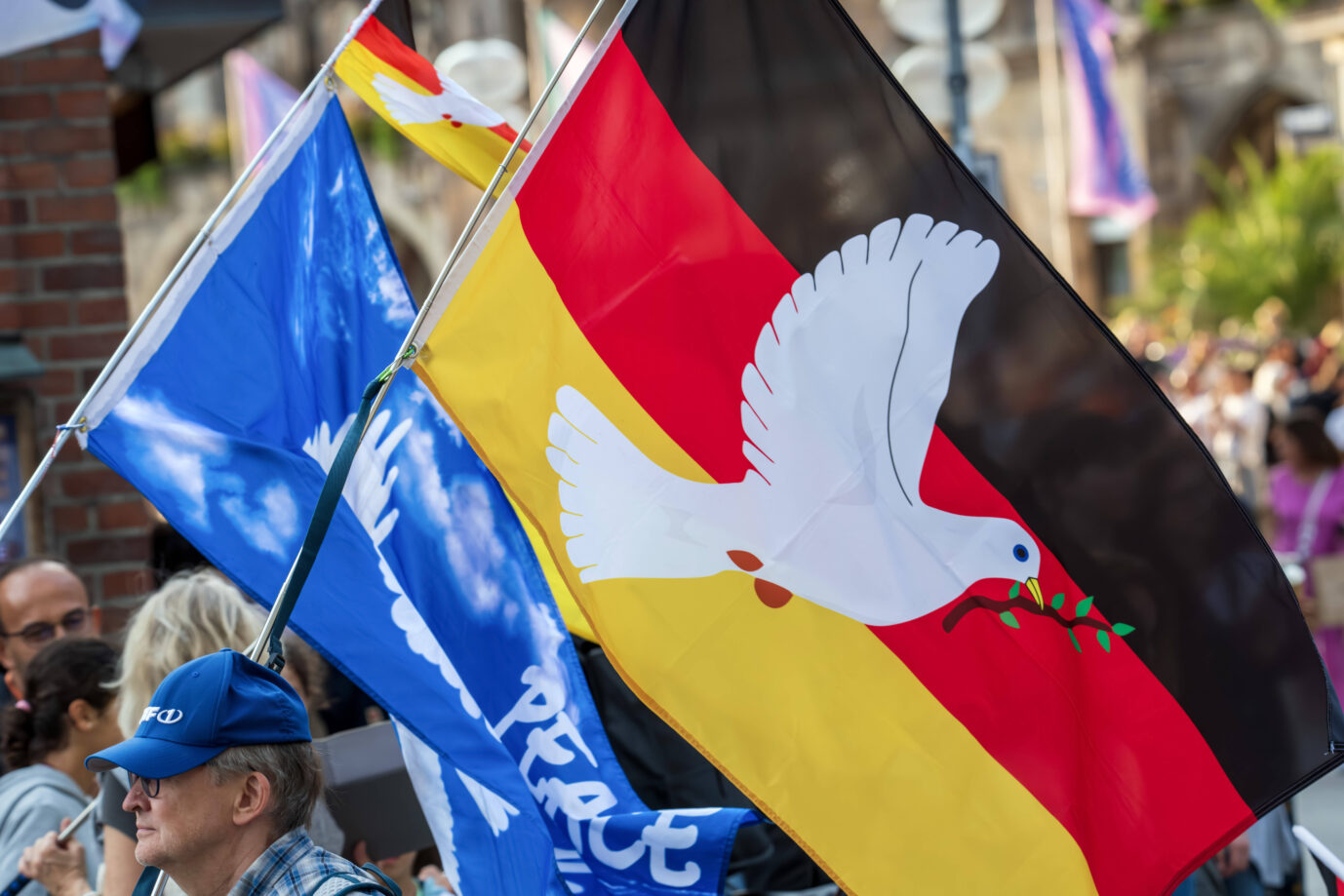 Deutschlandfahne mit Friedenstaube, Demo der Initiative München steht auf , München, 24. Juli 2024 Deutschland, München, 24. Juli 2024, Mittwochsumzug der Initiative München steht auf , Demonstrant mit Friedensfahne, Deutschlandflagge mit Friedenstaube, Umzug unter dem Motto Frieden, Freiheit, Selbstbestimmung , Demozug von ca. 100 Teilnehmern durch die Innenstadt, Mittwochabend um 19 Uhr, Demo jeden Mittwoch, die politisch rechte Initiative München steht auf ist die frühere Querdenker-Bewegung, Politik, Bayern, *** German flag with peace dove, demonstration of the initiative Munich stands up, Munich, July 24, 2024 Germany, Munich, July 24, 2024, Wednesday parade of the initiative Munich stands up, demonstrator with peace flag, G Deutschlandfahne mit Friedenstaube: Kapitulation gehört zur DNS.Deutschlandfahne mit Friedenstaube: Kapitulation gehört zur DNS. Foto: IMAGO / Wolfgang Maria Weber