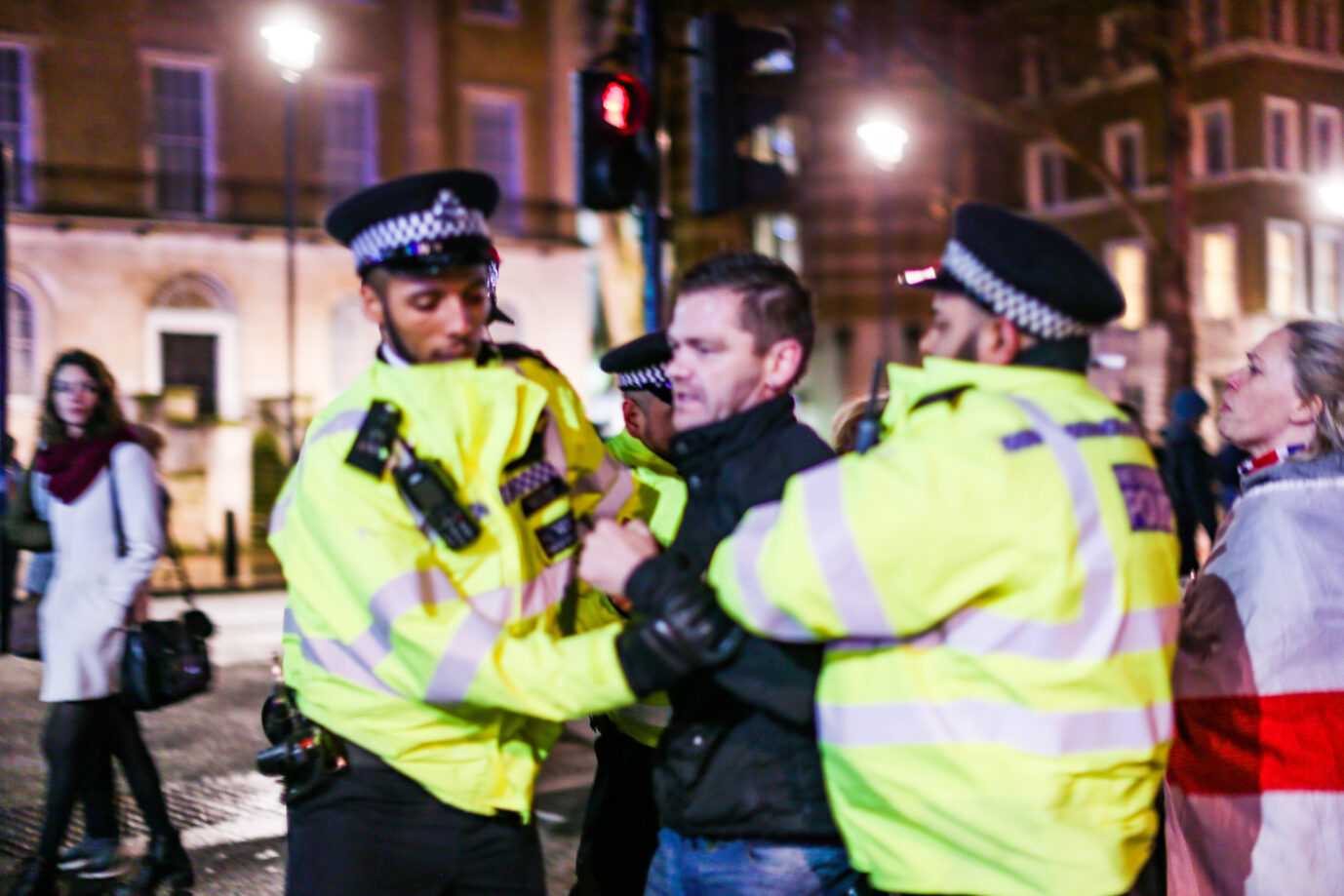 Zwei britische Polizisten mit gelben Warnjacken verhaften einen Brexit-Sympathisanten, der „rassistische Parolen“ gebrüllt haben soll – ein Sinnbild für den Zustand der Meinungsfreiheit in Großbritannien