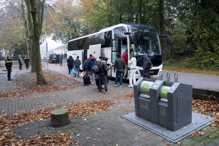 Auf einem Parkplatz steht ein großer Reisebus, daraus steigen migrantisch aussehende Männer - Symbolbild für die vielen Asylverfahren, die derzeit Sachsen belasten