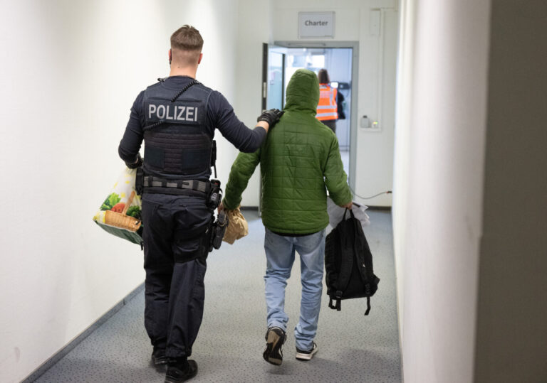 Ein Bundespolizist begleitet einen Migranten, der bei seiner Abschiebung nach Pakistan geflogen wird.