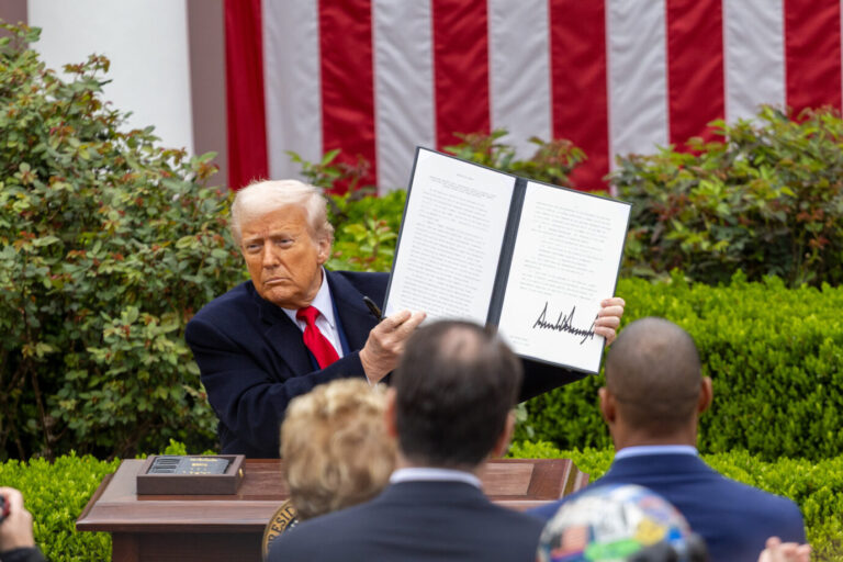 US-Präsident Donald Trump sitzt im Freien an einem Tisch und hält ein Blatt Papier hoch - es ist ein Bild vom April 2025, wo Trump seine reziproken Zölle präsentierte - ein US-Gericht hat diese nun gestoppt