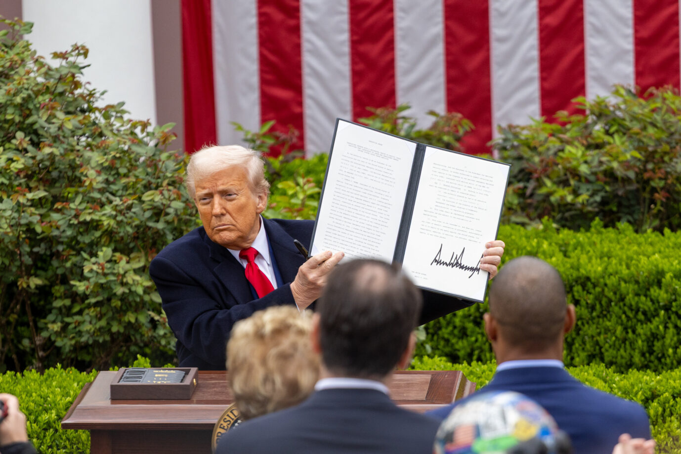US-Präsident Donald Trump sitzt im Freien an einem Tisch und hält ein Blatt Papier hoch - es ist ein Bild vom April 2025, wo Trump seine reziproken Zölle präsentierte - ein US-Gericht hat diese nun gestoppt