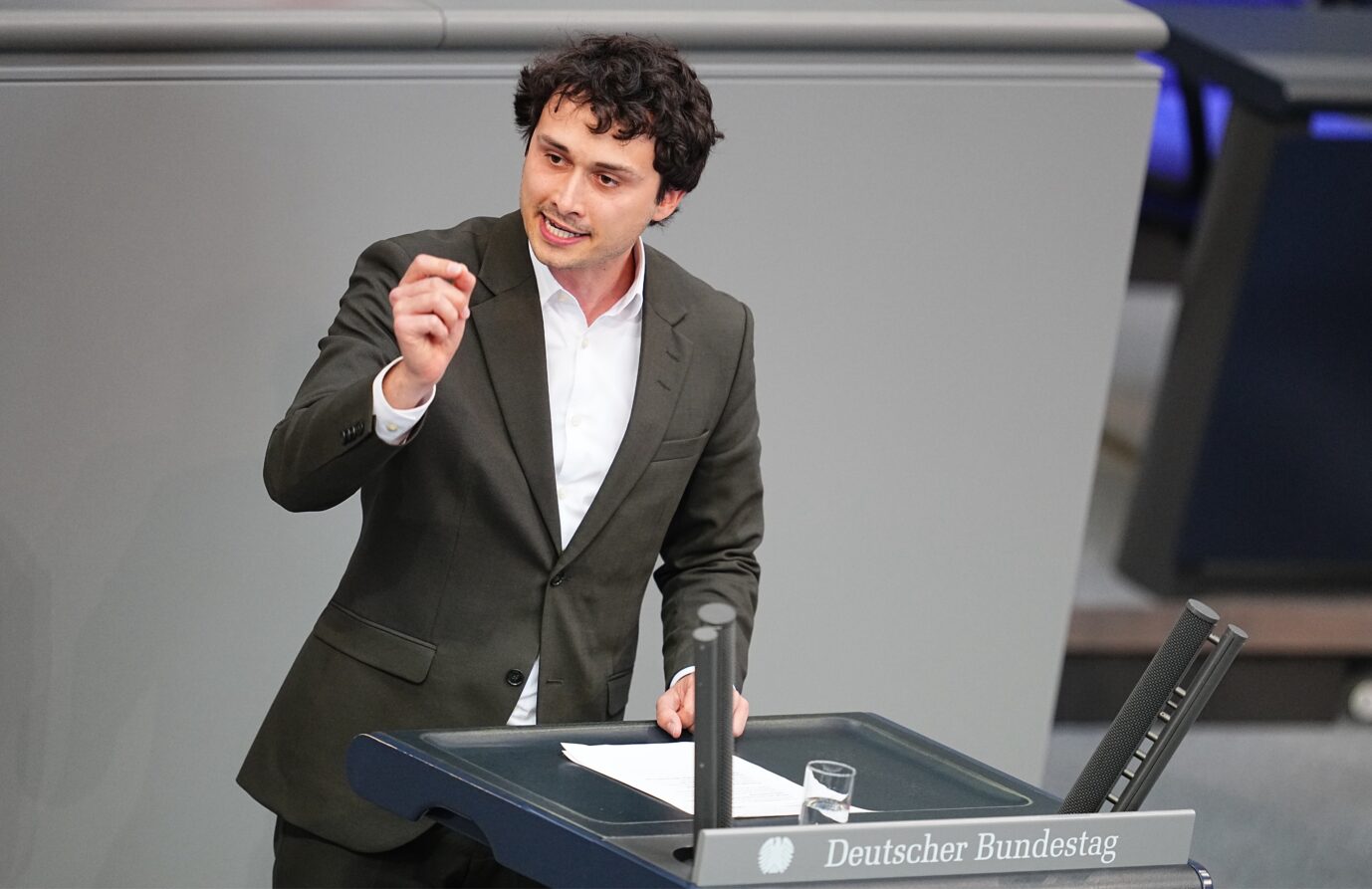 Ein junger Mann im dunklen Anzug und weißem Hemd spricht engagiert am Rednerpult des Deutschen Bundestags. Er gestikuliert mit der rechten Hand, vor ihm liegen Papiere und ein Glas Wasser. Auf dem Pult steht deutlich sichtbar die Aufschrift „Deutscher Bundestag“. Am Mittwochnachmittag diskutiert der Bundestag über geschliffene Küchenmesser und – weil den rot-grünen Rednern das Thema nicht paßt – auch über rechte Gewalt. Schuld an beiden soll ein und dieselbe Partei haben. Lukas Benner (Grüne) spricht im Bundestag. Foto: picture alliance/dpa | Michael Kappeler