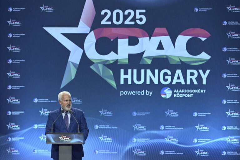 Vor einem blauen Hintergrund ist das Logo der CPAC Hungary 2025 zu sehen, davor steht der Vorsitzende der American Conservative Union, Matthew Schlapp, und hält eine Rede
