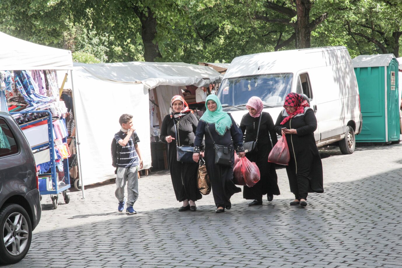 Auf einer Straße sieht man Frauen mit Kopftüchern, daneben ein kleines migrantisches Kind – Symbolbild für Familiennachzügler