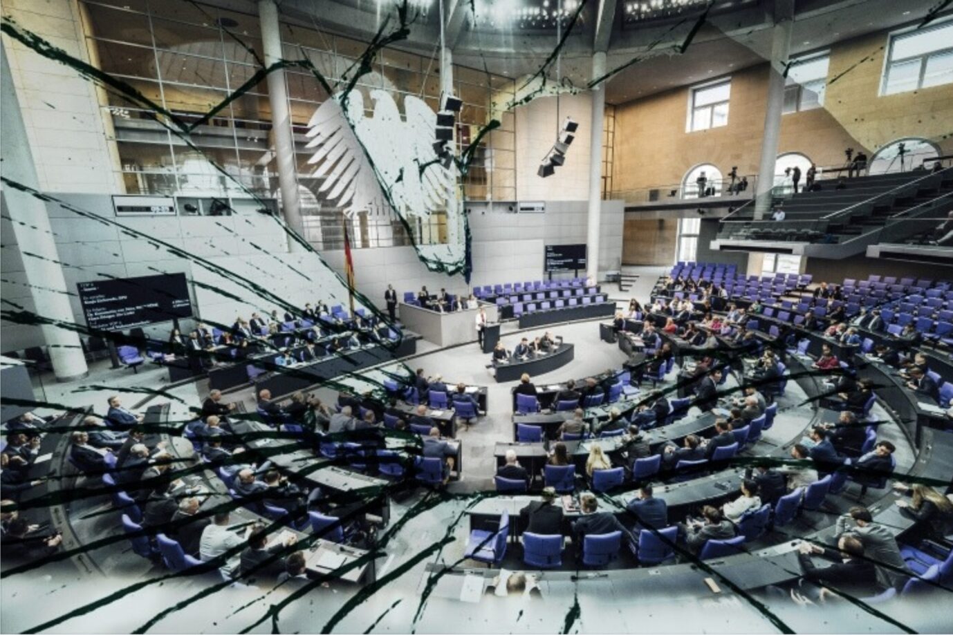 Auf dem Foto ist eine Sitzung im Deutschen Bundestag zu sehen – es ist darauf aber ein Effekt gelegt, der aussieht, als sei das Glas des Bildschirm gesplittert – es ist ein Symbolbild für die brüchige Demokratie