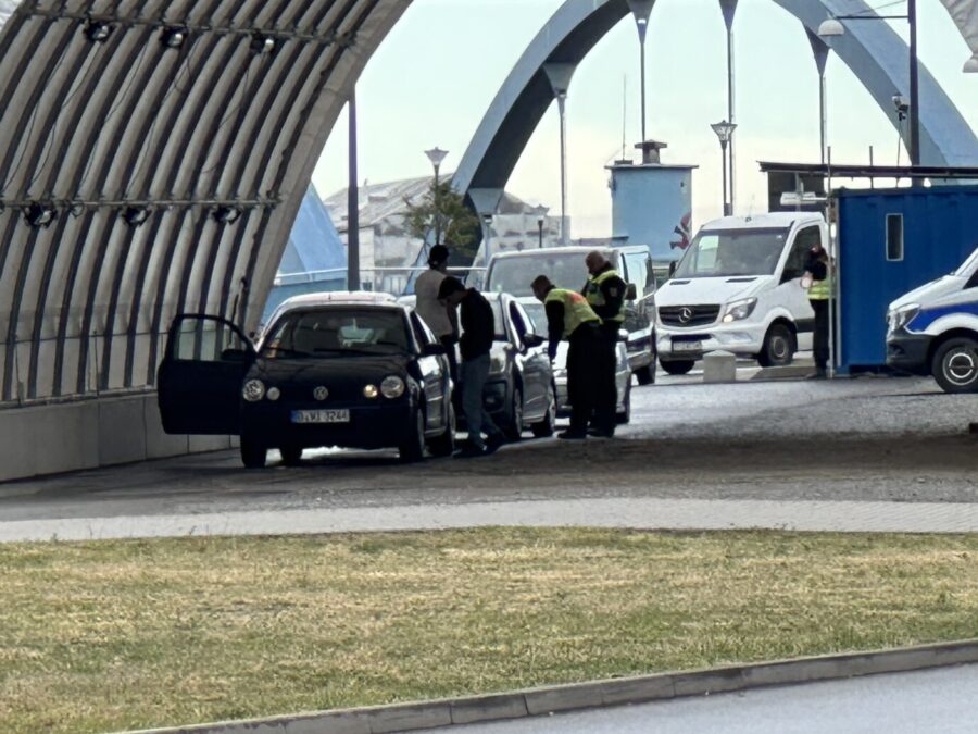 Unter einem Wellbelchdach sieht man ein stehendes Auto und darum Polizisten in gelben Warnwesten, die das Auto an der deutsch-polnischen Grenze nach illegalen Migranten durchsuchen