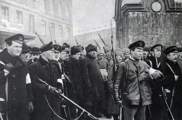 Auf einem alten schwarz-weiß-Foto sind bwaffnete revoltierende Soldaten und Bürger zu sehen, die grimmig gucken und auf einer Straße in Sankt Petersburg (damals Petrograd) stehen – während der Februarrevolution 1917, als der Zar gestürzt wurde