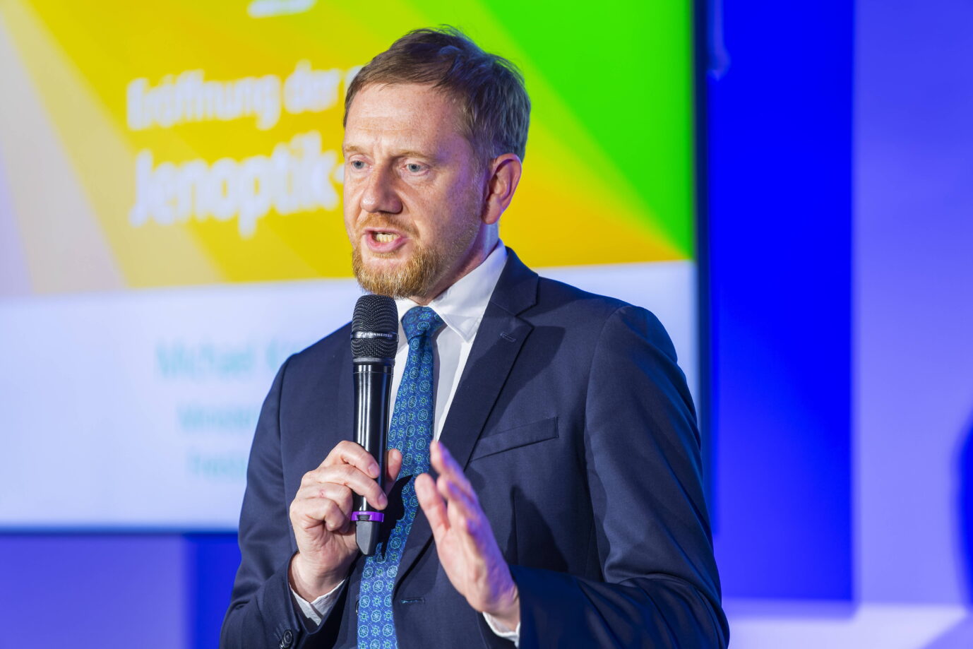 Der sächsische Ministerpräsident Michael Kretschmer (CDU) steht mit blauem Schlips und blauem Jackett auf einer Bühne und gestikuliert – vielleicht fordert er gerade einen anderen Umgang mit der AfD