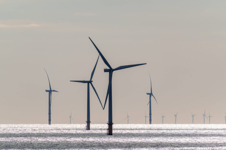 Vier Windräder stehen im Meer herum – Symbolbild für die deutsche Stromversorgung