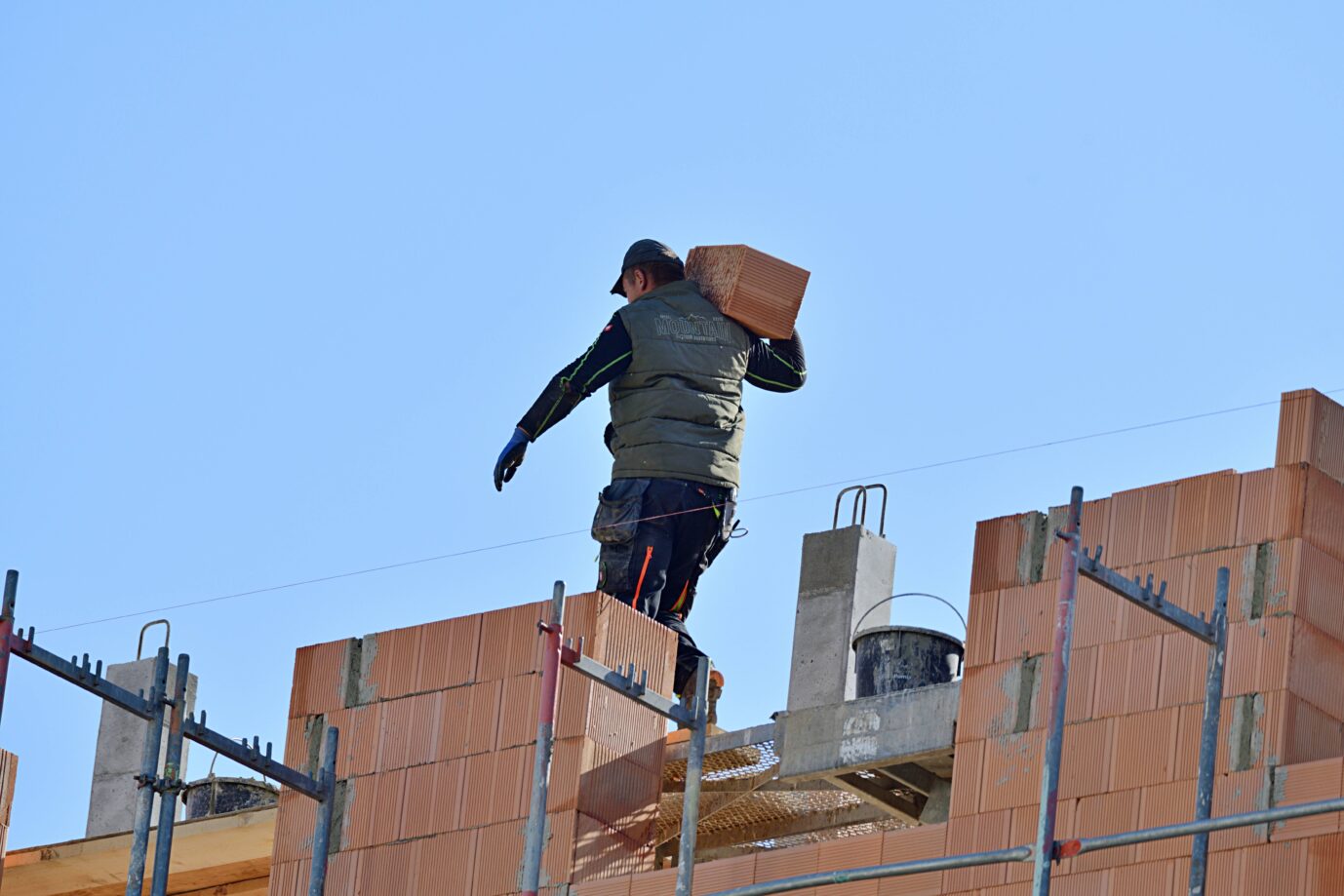 Ein Bauarbeiter schleppt ein Mauerstück auf einer Baustelle. Die Zahl der neuen Wohnungen in Deutschland sinkt.