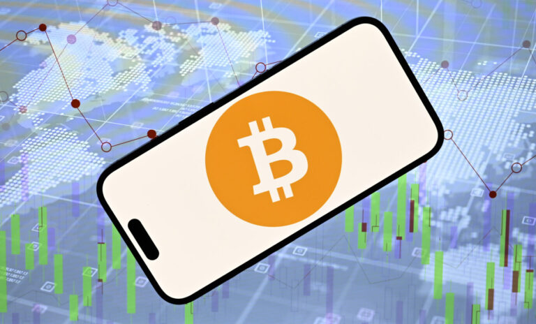 Das Bild zeigt das „Bitcoin“-Logo vor einer digitalen Weltkarte. Es ist ein Symbolbild für Cryptowährungen und das globale Geldsystem.