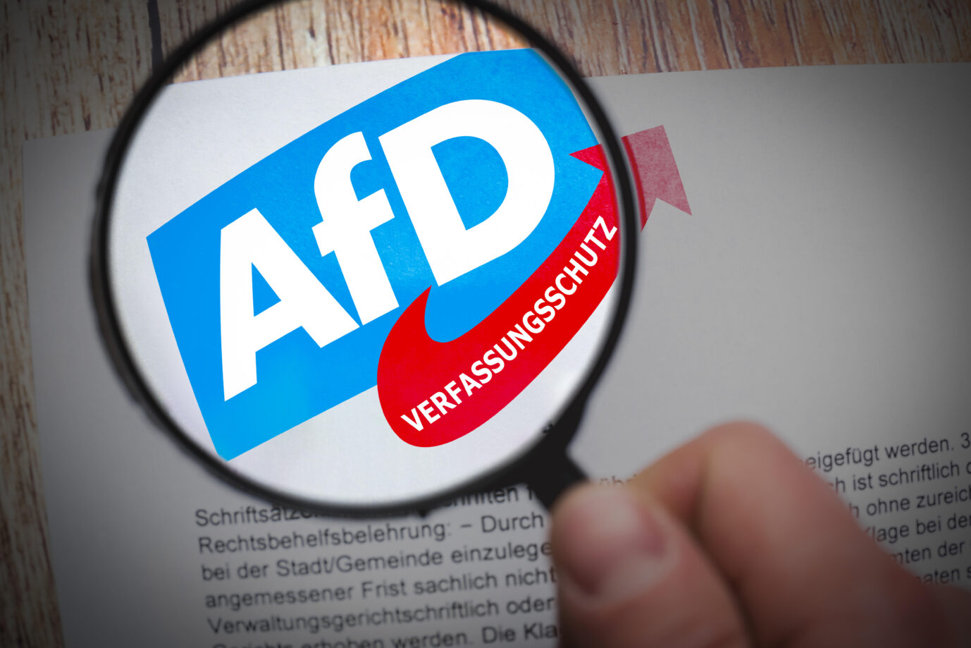 FOTOMONTAGE, Lupe über dem AfD-Logo mit dem Zusatz Verfassungsschutz betont die genaue Beobachtung der Partei durch staatliche Stellen wegen möglicher verfassungsfeindlicher Bestrebungen.