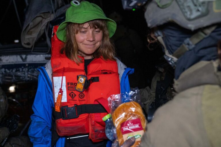 Greta Thunberg freut sich über ein Sandwich, das ihr eine israelische Soldatin auf einem Boot überreicht.