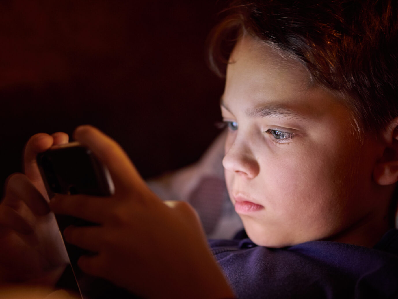 Ein Junge spielt mit einem Handy. Thema der Meldung: Sprachstörungen bei Kindern und Jugendlichen. Ist das Handy schuld?