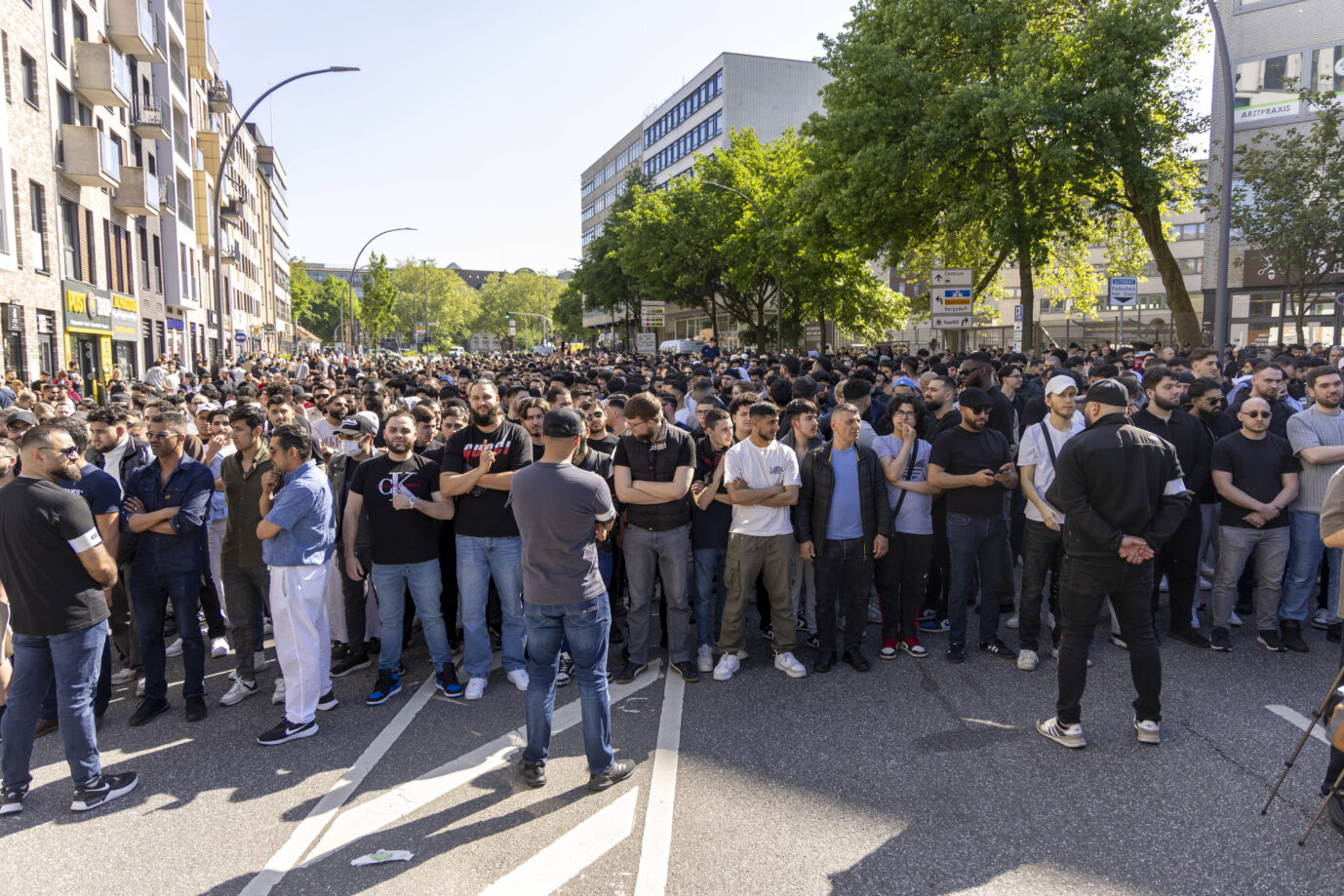Eine große Menschenmenge steht dicht gedrängt auf einer innerstädtischen Straße bei Sonnenschein. Fast ausschließlich junge Männer, viele mit verschränkten Armen, richten den Blick nach vorn. Im Vordergrund stehen mehrere Männer in Gesprächsposition. Im Hintergrund sind Bäume, Wohnhäuser und Arztpraxen zu sehen. Eine neue Untersuchung wirft ein Schlaglicht auf innerislamische Konflikte: Viele Muslime in Deutschland befürworten autoritäre und gewaltlegitimierende Positionen. Die Gründe dafür sind vielfältig. Radikale Muslime demonstrieren am Hamburger Steindamm: Eine Studie klärt über das Gefährdungspotential auf. Foto: Foto: IMAGO / Markus Matzel