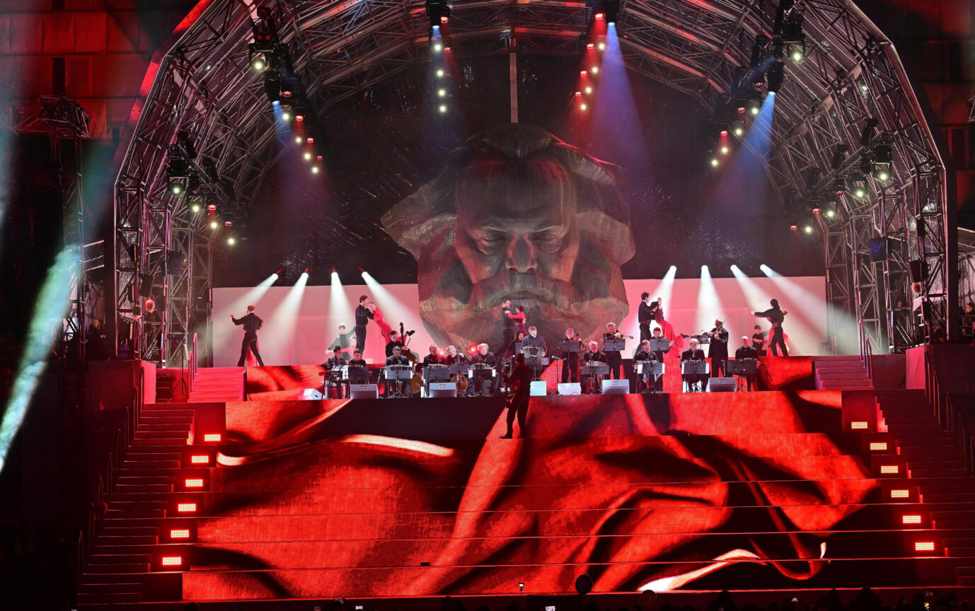 Der Karl-Marx-Kopf in Chemnitz wird rot angestrahlt, davor spielt eine Rockband – währen der Eröffnungsfeier für Chemnitz als Kulturhauptstadt Europas 2025