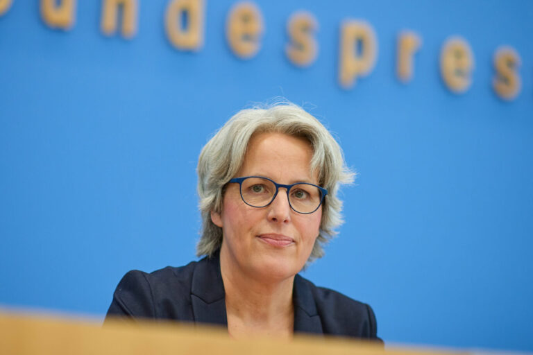 Kerstin Claus, die Unabhängige Beauftragte für Fragen des sexuellen Kindesmißbrauchs der Bundesregierung, sitzt während einer Pressekonferenz vor blauem Hintergrund mit dem Schriftzug der Bundespressekonferenz. Sie trägt eine dunkle Jacke und eine Brille mit blauem Rahmen. Claus blickt ruhig und ernst in Richtung Kamera. Kerstin Claus bei der Bundespressekonferenz in Berlin: Die Mißbrauchsbeauftragte fordert strengere Gesetze zum Schutz von Kindern im Netz. Foto: IMAGO / epd