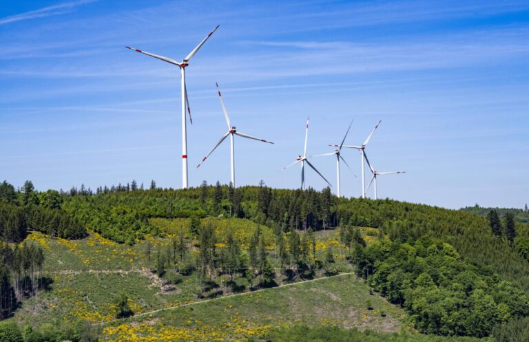 Vor einem blauen Himmel drehen sich mehrere Windräder – Symbolbild für deutsche Stromerzeugung