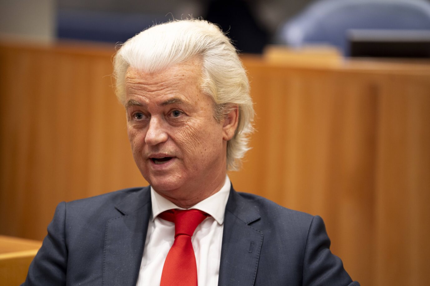 Der Vorsitzende der PPV, Geert Wilders, sitzt im niederländischen Parlament und trägt einen blauen Anzug und eine rote Krawatte