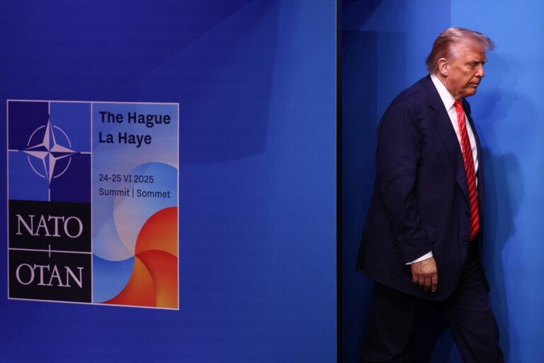 US-Präsident Donald Trump läuft vor einer blauen Wand, links von ihm ist das Logo des Nato-Gipfels 2025 zu sehen