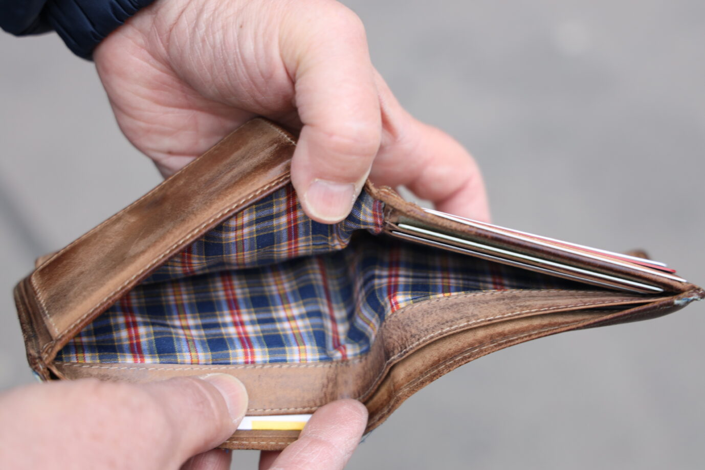 zwei Hände öffnen eine leere Geldbörse – Symbolbild dafür, daß die Verschuldung der Gemeinden, Kommunen und aller öffentlichen Strukturen 2024 immens war