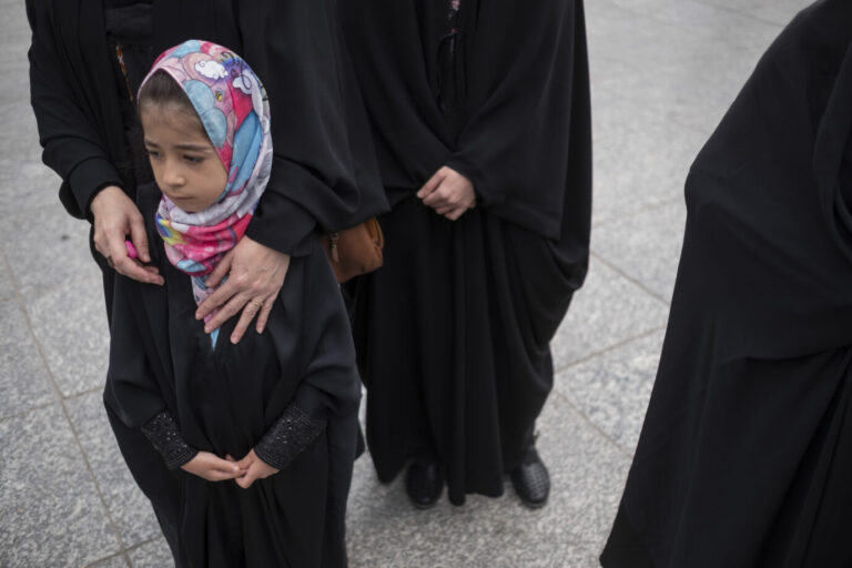 Auf einer Straße steht ein kleines Mädchen mit Kopftuch, daneben einige vollverschleierte Frauen – Symbolbild für die Zwangsheirat