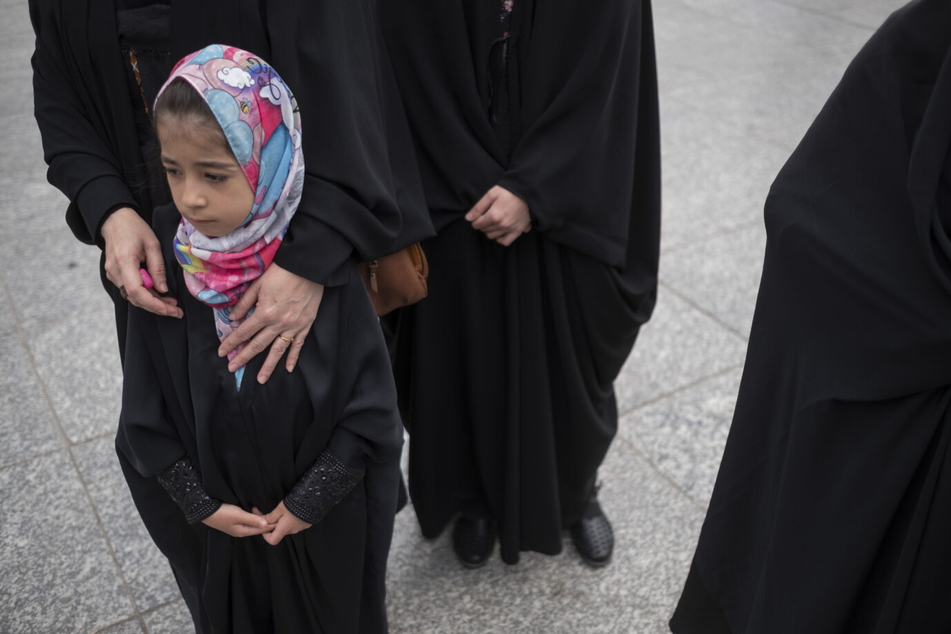 Auf einer Straße steht ein kleines Mädchen mit Kopftuch, daneben einige vollverschleierte Frauen – Symbolbild für die Zwangsheirat