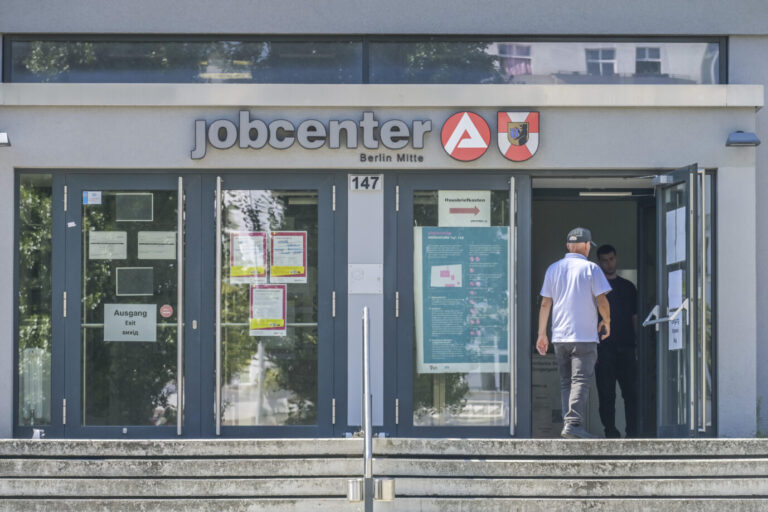 Ein älterer Mann im Hemd betritt eine Dienststelle der Agentur für Arbeit – vielleicht ist er arbeitslos, so wie immer mehr Menschen in Deutschland