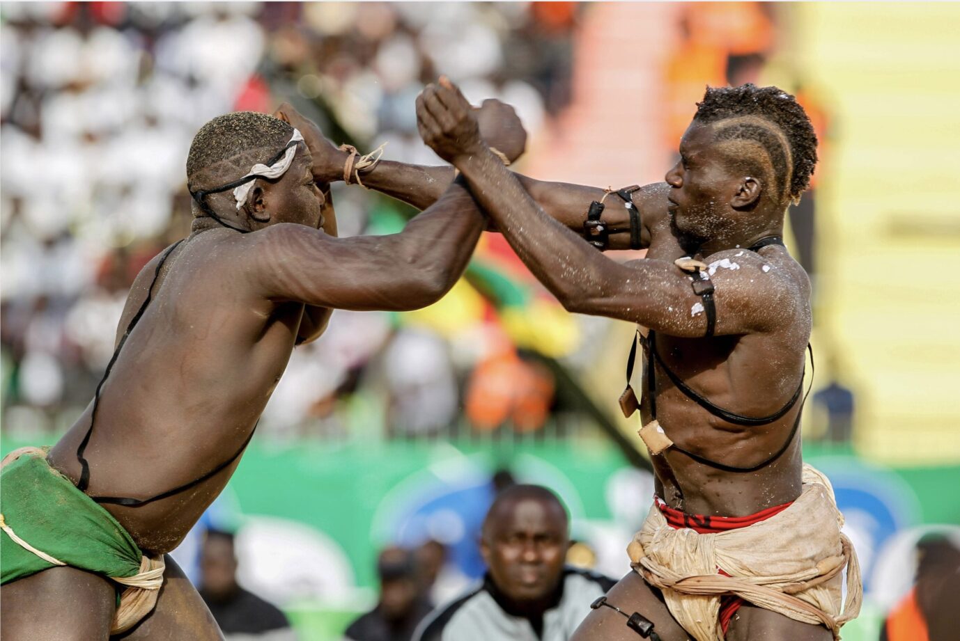 Zwei schwarze Männer stehen sich gegenüber und kämpfen – es handelt sich um zwei Teilnehmer eines traditionellen Wrestling-Turniers in Gambia.