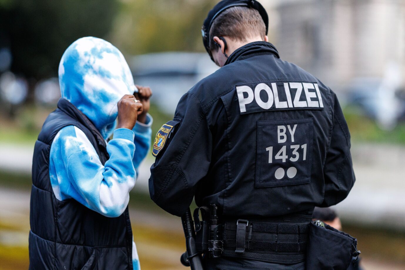 Ein bayerischer Polizist kontrolliert einen Ausländer, der sein Gesicht verdeckt. Syrer und Afghanen sind häufiger kriminalitätsbelastet als Deutsche.