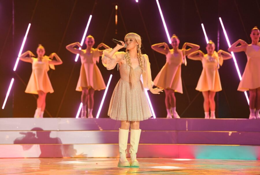 Auf einer Bühne steht eine cute osteuropäische Frau mit Zöpfen – es handelt sich um die weißrussische Sängerin Anastasia Krawtschenko, diem am 20. September beim Intervision Song Contest in Moskau antreten wird