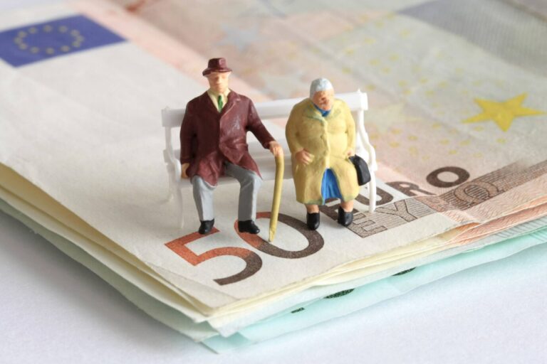 Rentner-Figuren auf einer Parkbank und einem Stapel Geld. Der Boomer-Soli soll die Rentner schröpfen.