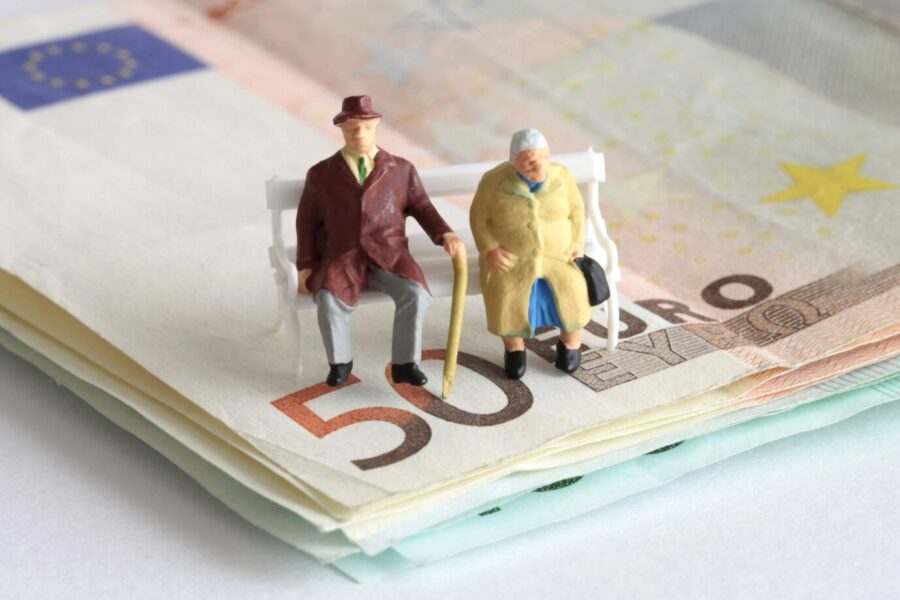 Rentner-Figuren auf einer Parkbank und einem Stapel Geld. Der Boomer-Soli soll die Rentner schröpfen.