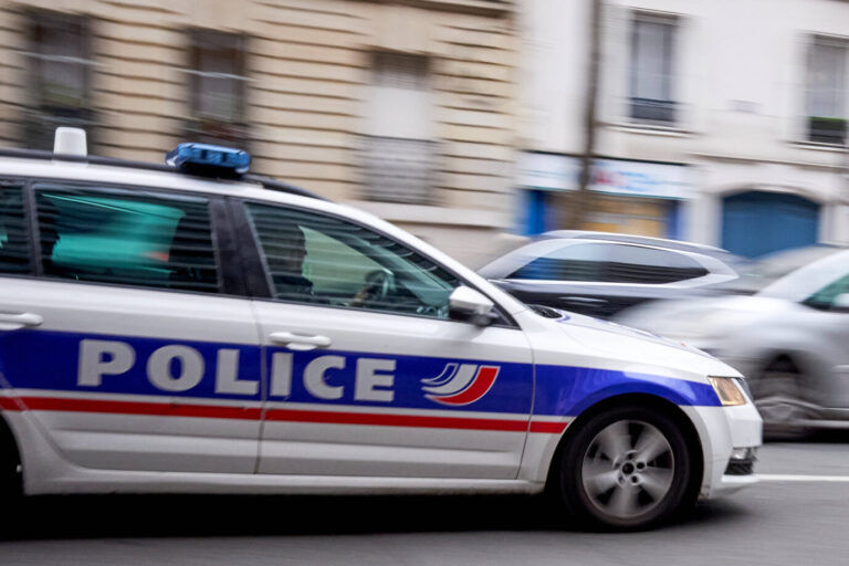 Durch die Straße einer französischen Stadt fährt ein Polizeiauto – vielleicht setzt es die Ausgangssperre von Nimes durch, die wegen der Drogenbanden verhängt wurde